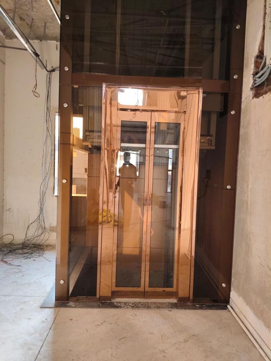 Rose-gold stainless steel and glass lift installed by Sigma Tex Engineering